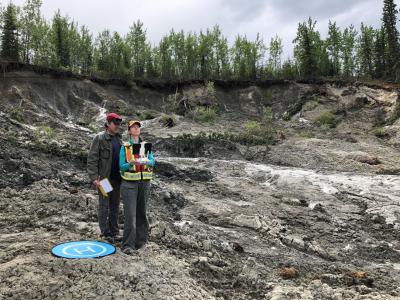 Two people operating a drone at a permafrost slump